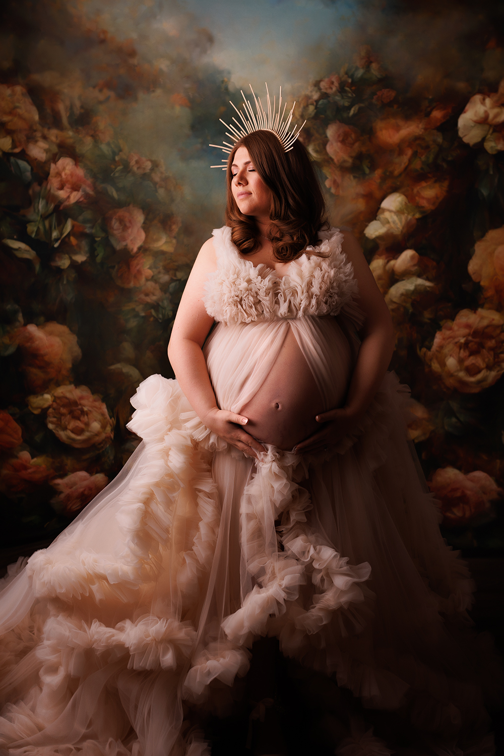 Beautiful mom to be in an ivory gown on a floral backdrop