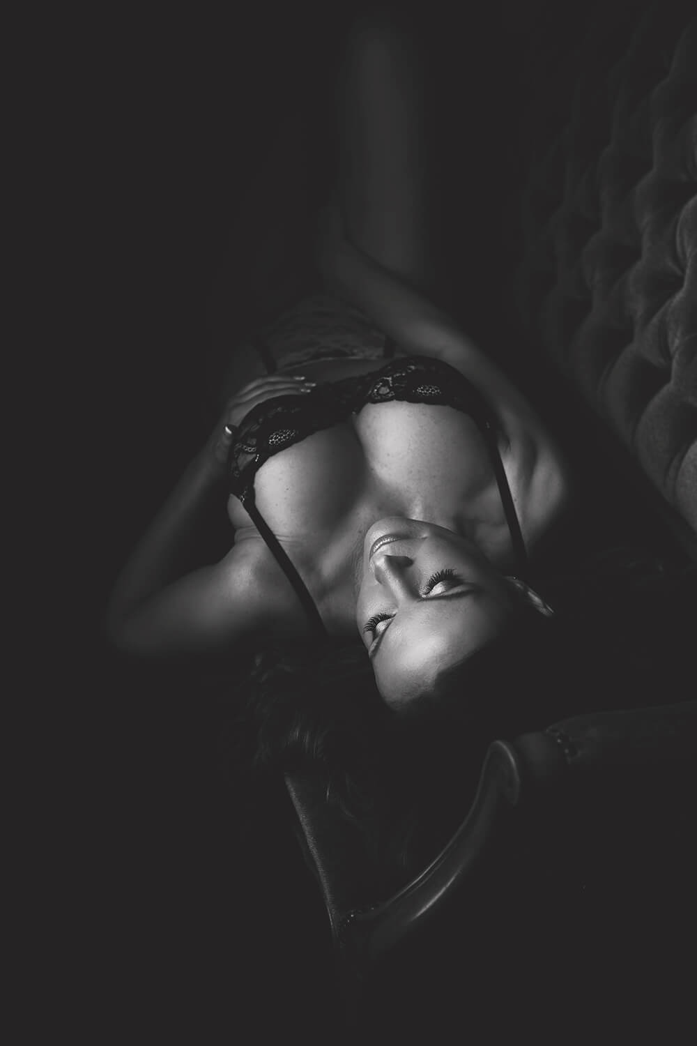 Black & white image of a woman laying on a couch in Lingerie by Toronto Boudoir Photographer Shanna Parker