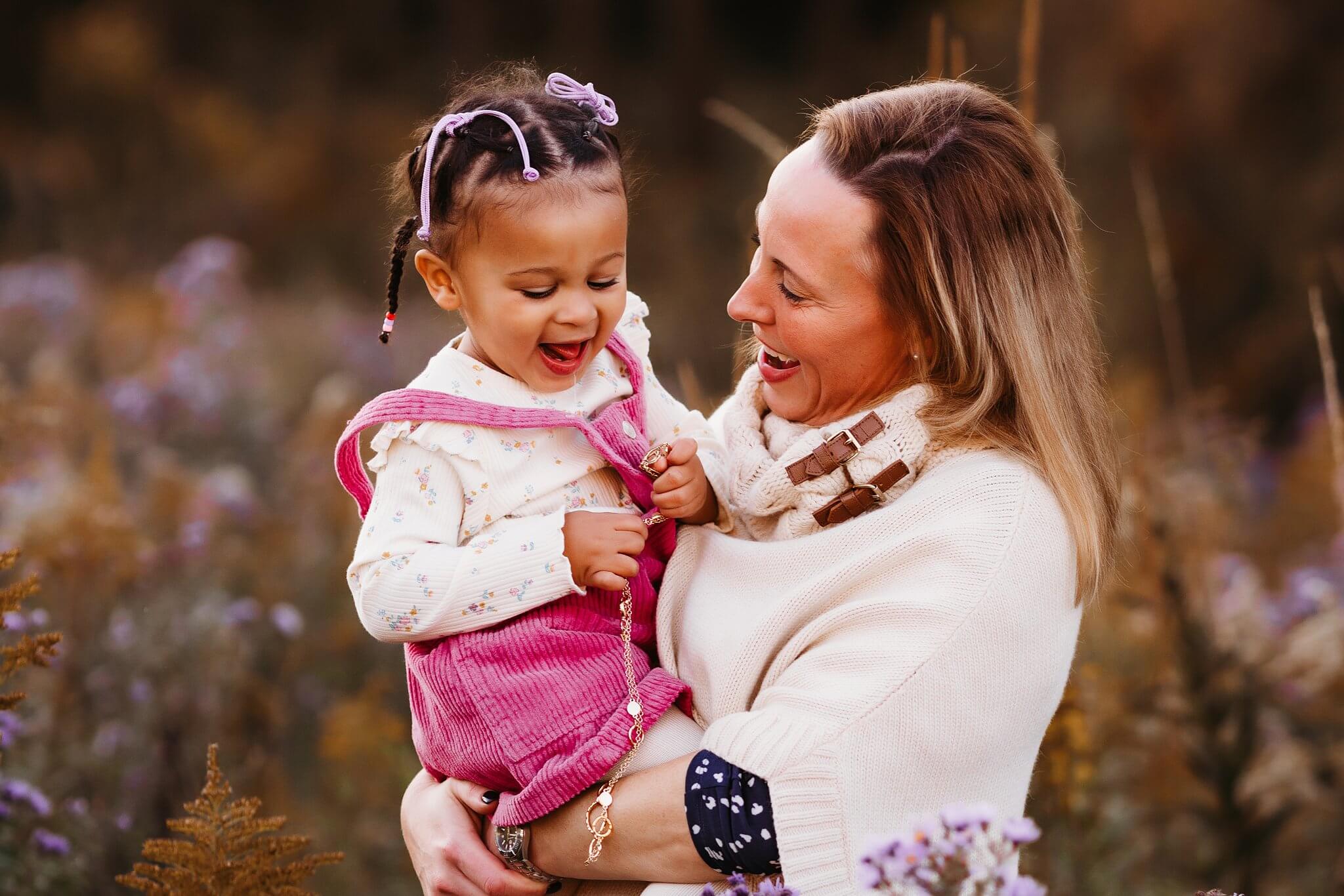 Photo showing the love between mother and toddler daughter standing in tall grasses and wildflowers