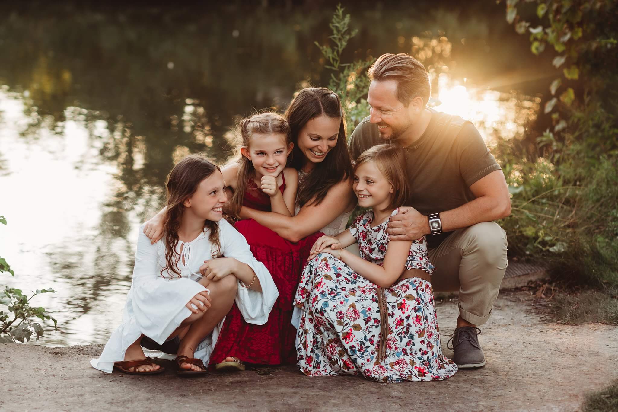 Photo by Toronto Family Photographer, Family snuggled together in front of water with the sun setting behind them