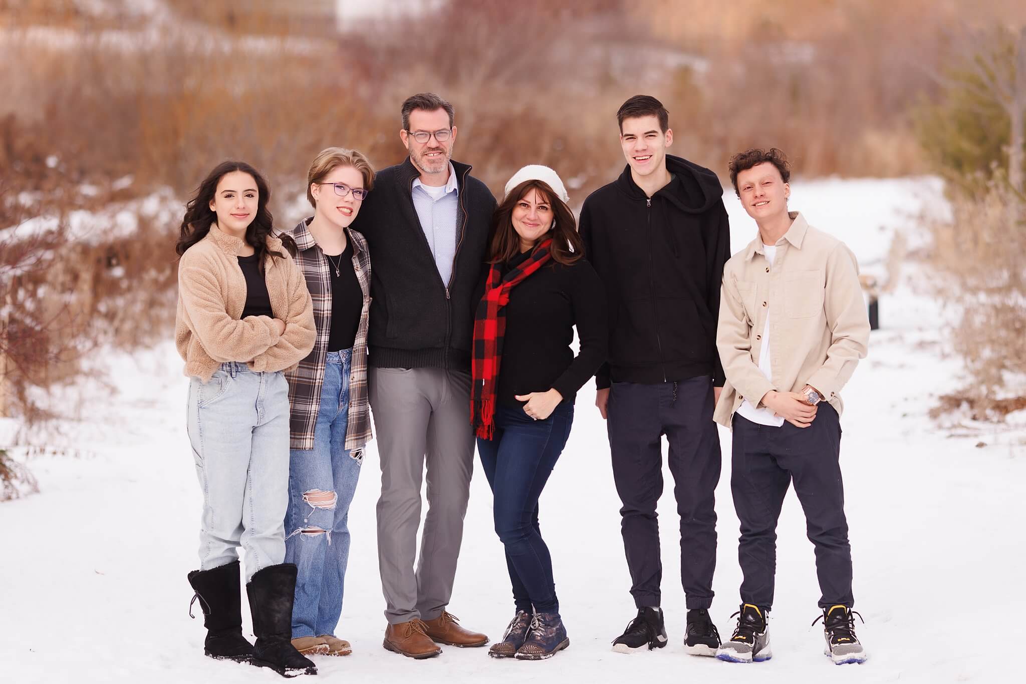 Winter family portrait, parents and their four teenage kids standing on a snowy path
