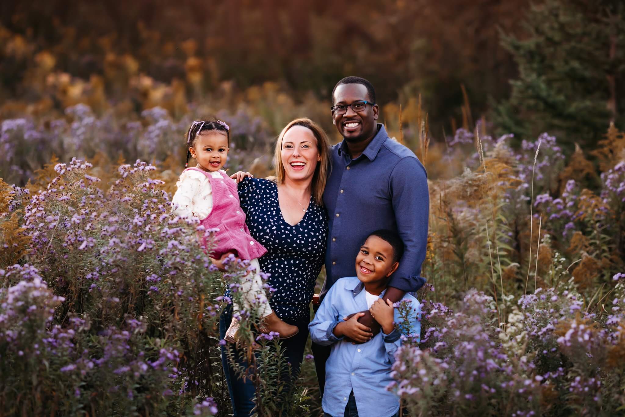 Family Posed together in wildflowers smiling at the camera by Toronto Family Photographer Shanna Parker