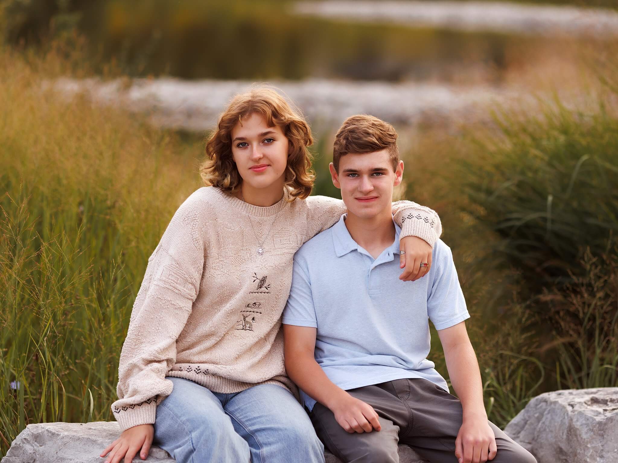 Brother and sister sitting on a rock with arms around each other