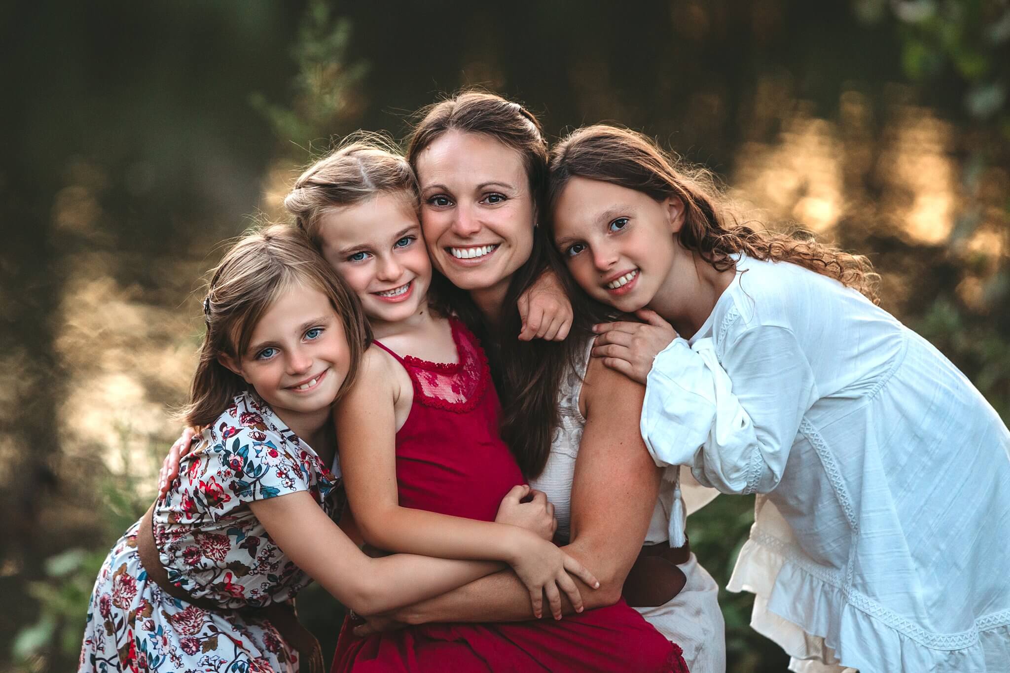 Mother and her three daughters snuggled together and smiling at the camera