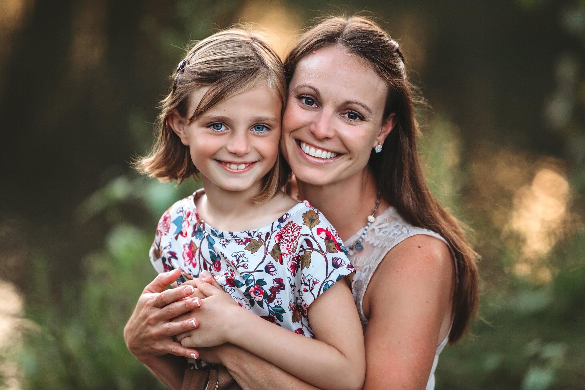 Mother and daughter at sunset smiling at the camera