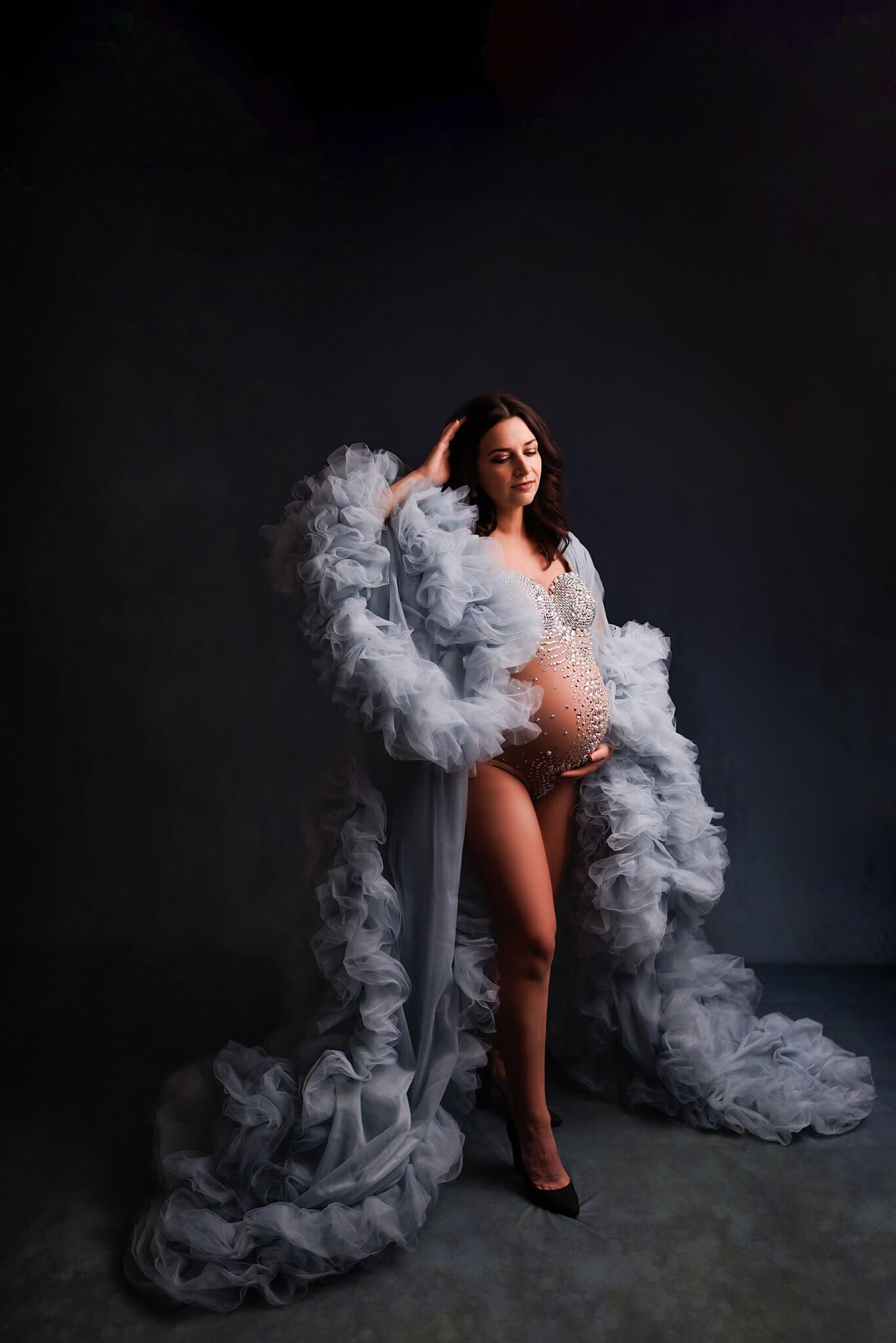 Toronto Maternity Photography showing a woman in a light blue extravagant gown and a sparkly bodysuit showing her pregnant belly