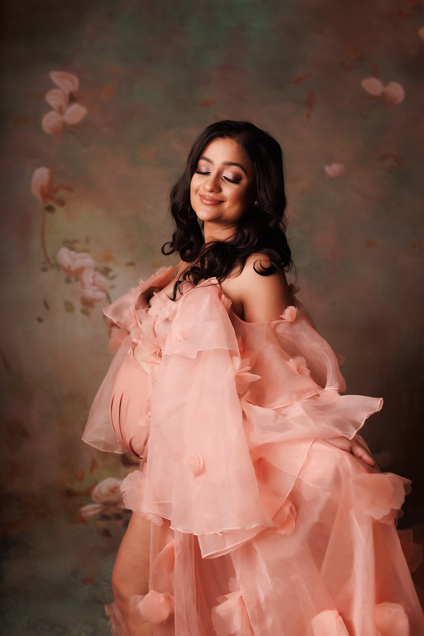 Barrie Maternity photography of a Beautiful woman in a coral maternity gown on a floral backdrop