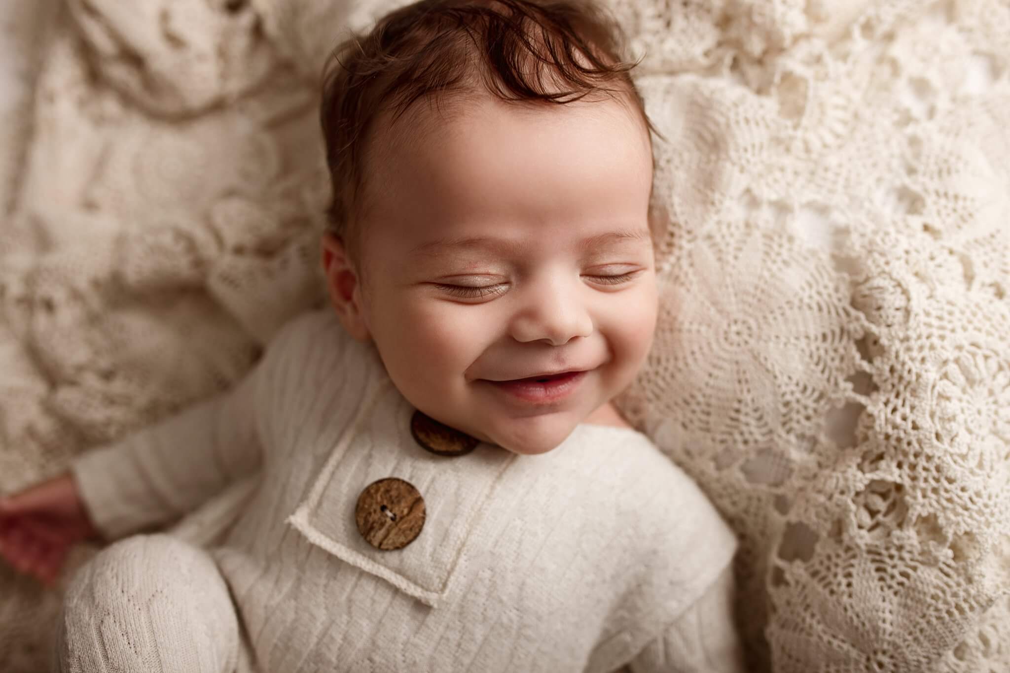 Smiling baby boy on white crochet blanket