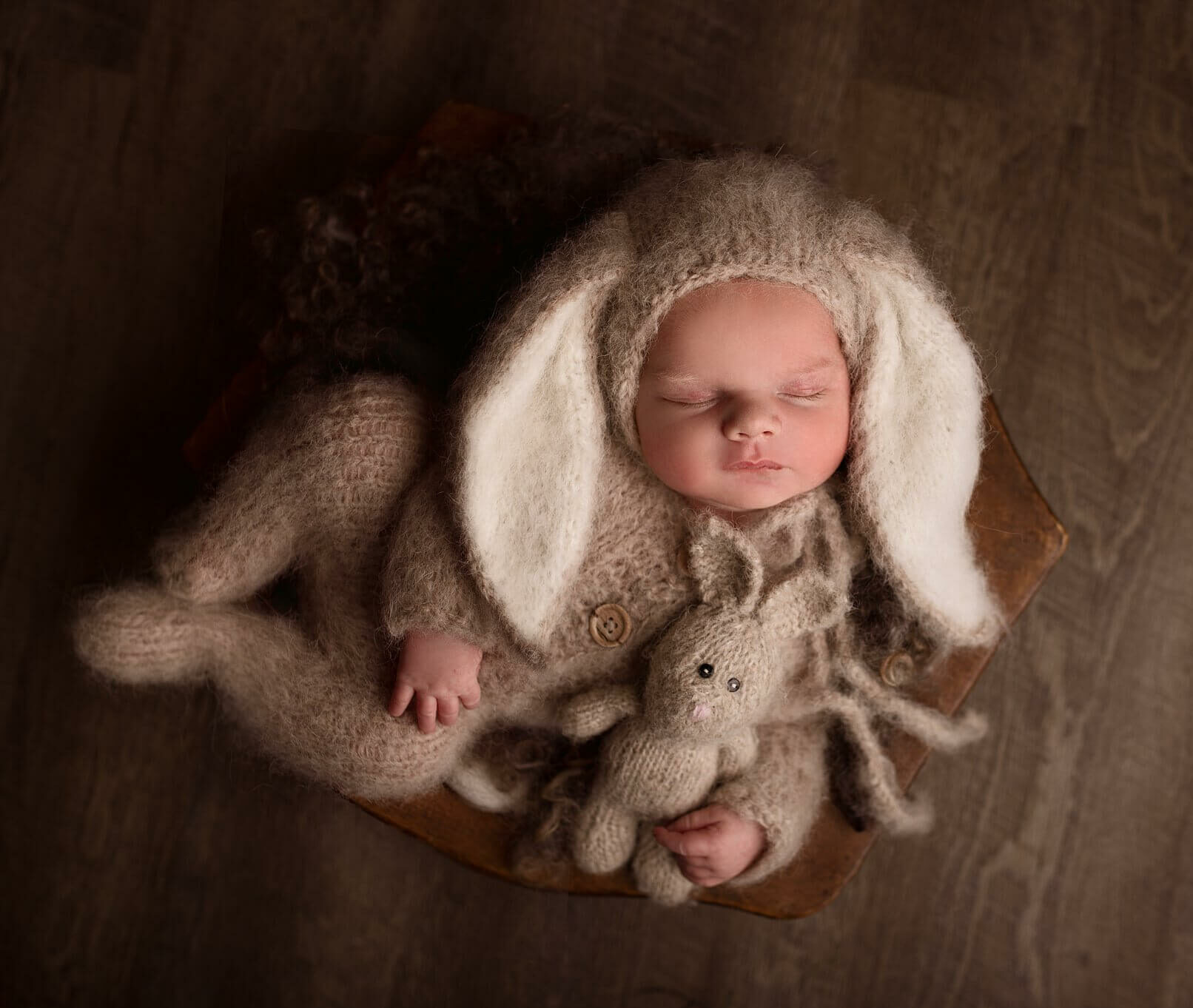 Newborn boy in a knit bunny hat and romper holding a knit bunny stuffy by Toronto Newborn Photographer