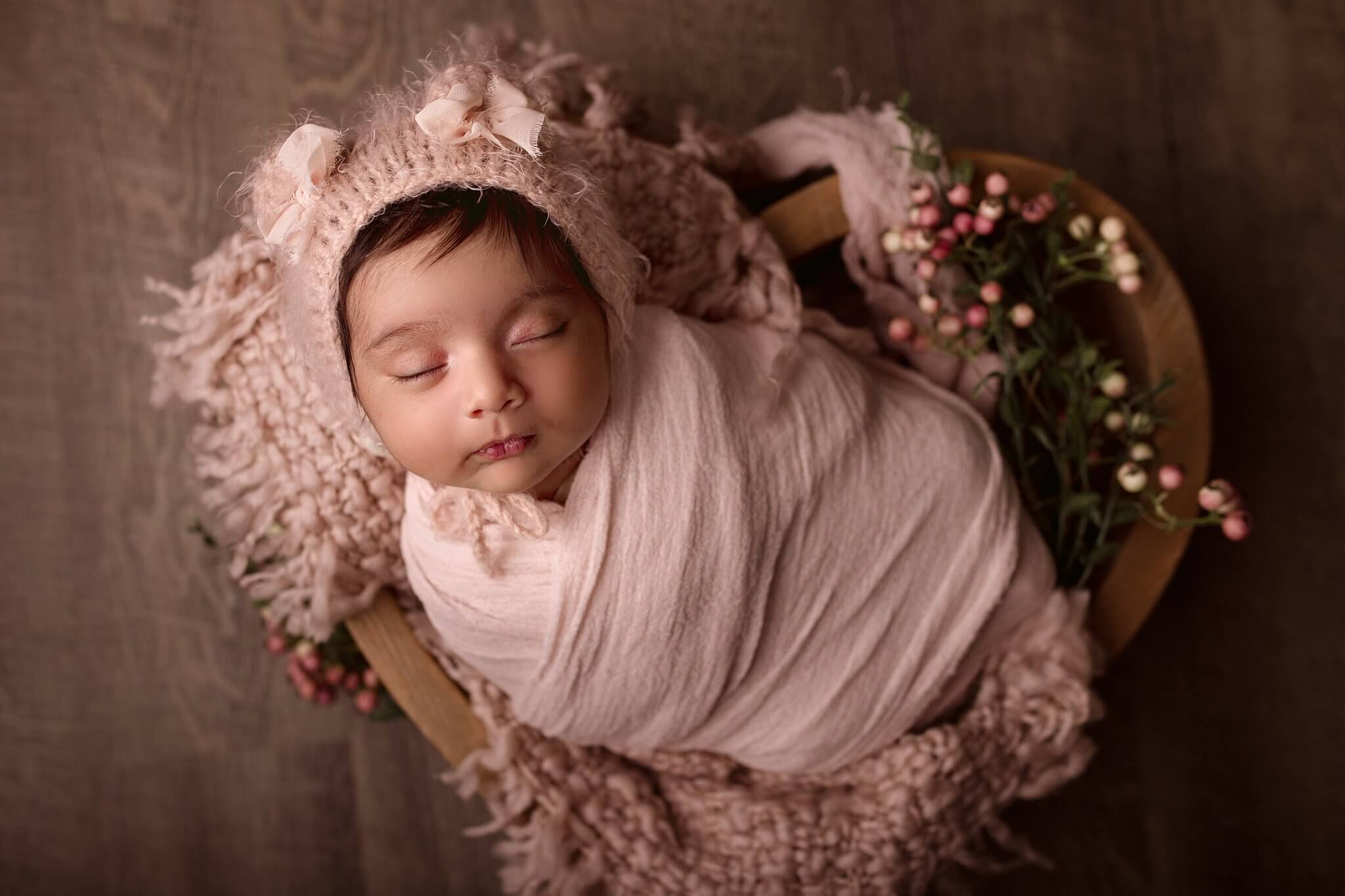 Newborn Baby Girl in a fuzzy bear hat swaddled in light pink in a heart bowl by Toronto Newborn Photographer