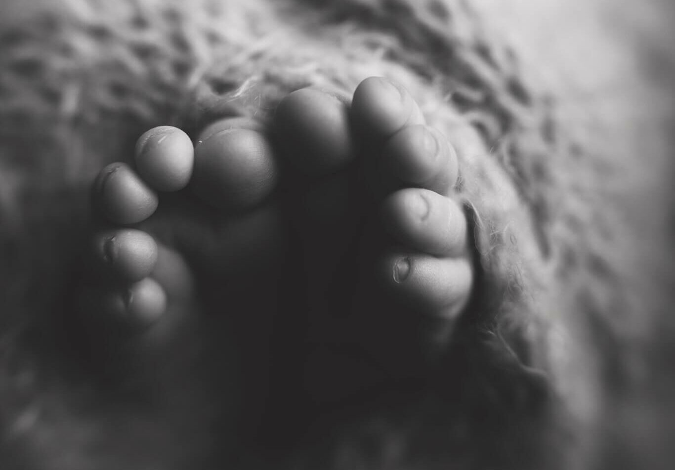 Black and white image of adorable baby toes wrapped in a blanket