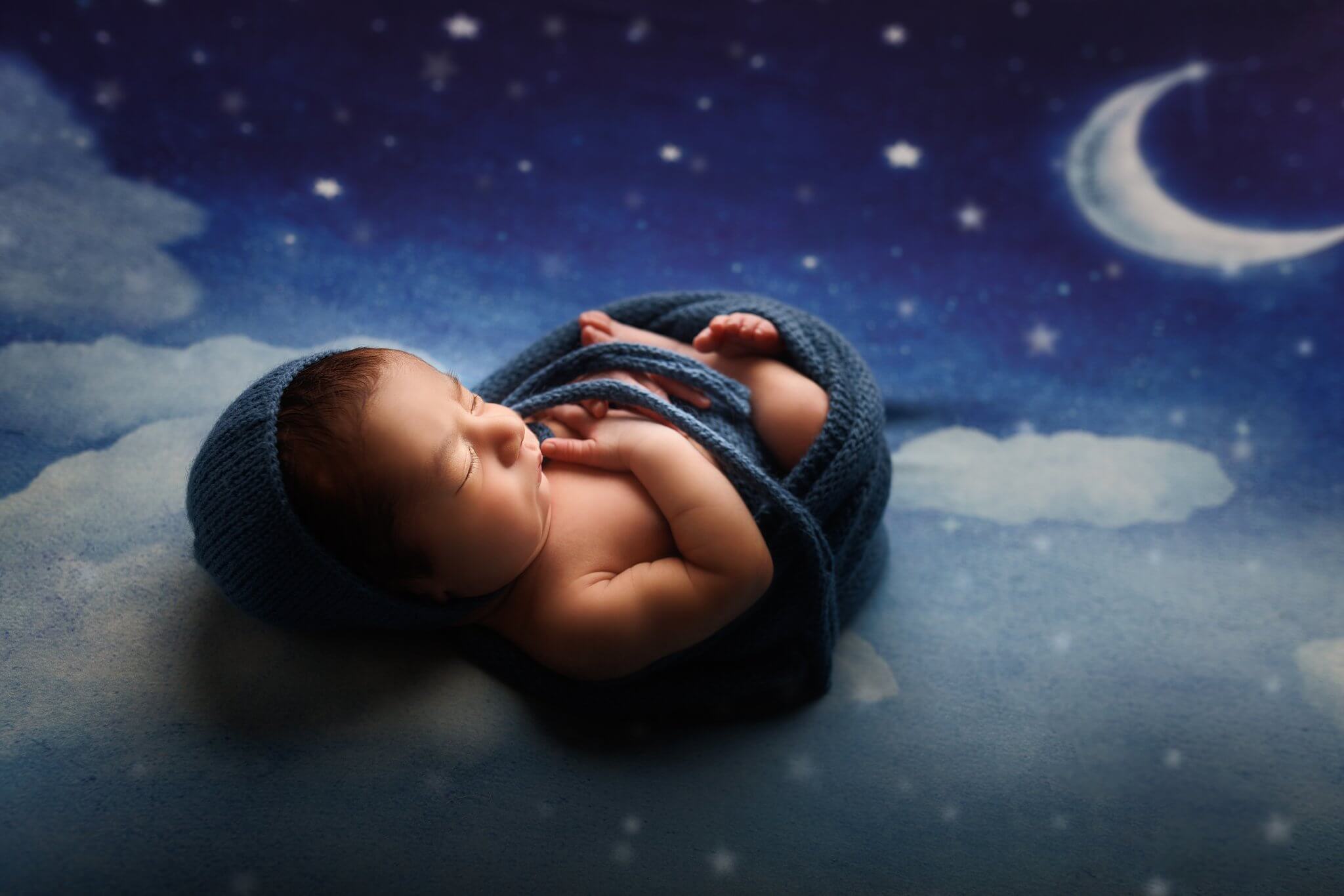 Newborn Baby boy wrapped in blue on a moon and stars backdrop