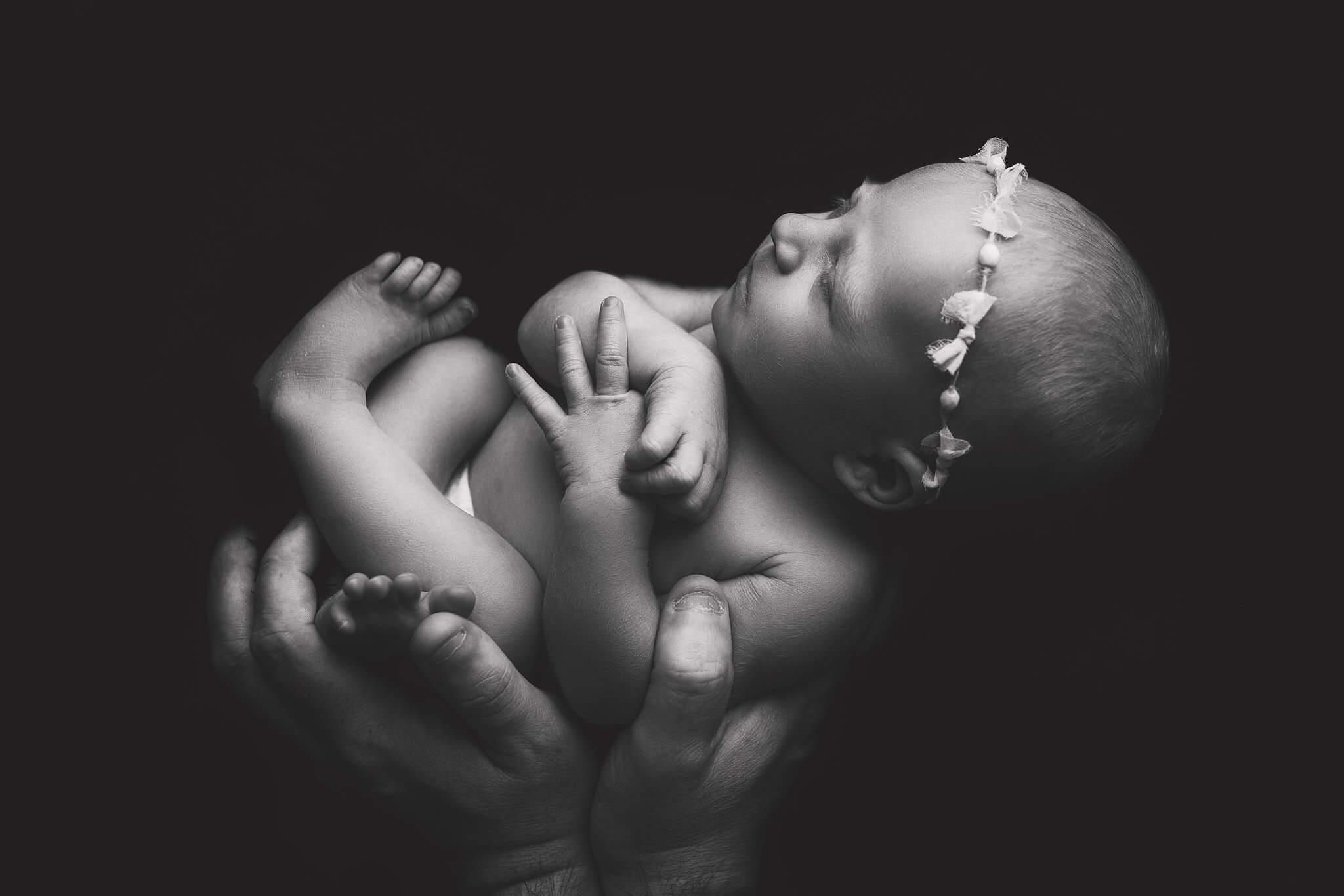 Black and white image of a newborn baby girl in her daddy's hands