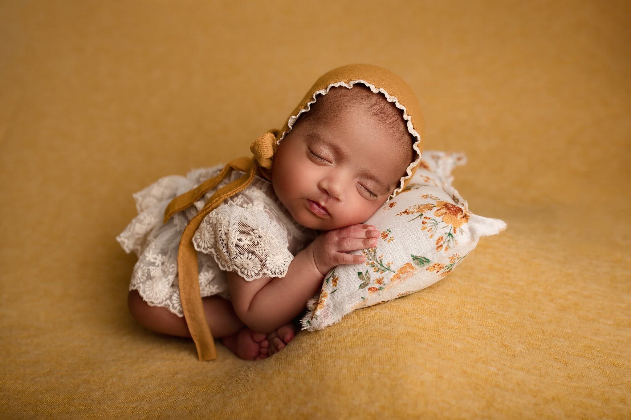 Toronto Newborn Photography photo of a Newborn girl in a lace outfit and mustard bonnet on mustard blanket