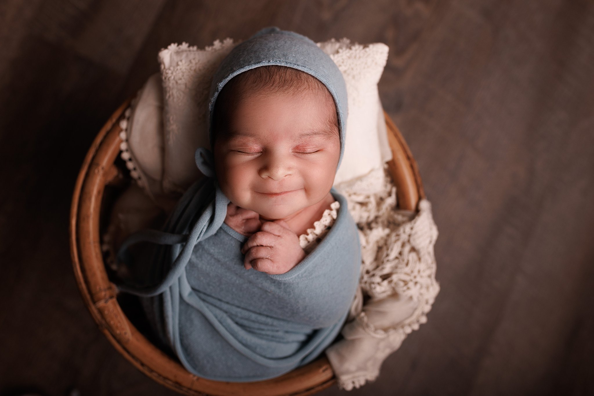 newborn baby sleeps swaddled in a blue blanket smiling baby furniture toronto