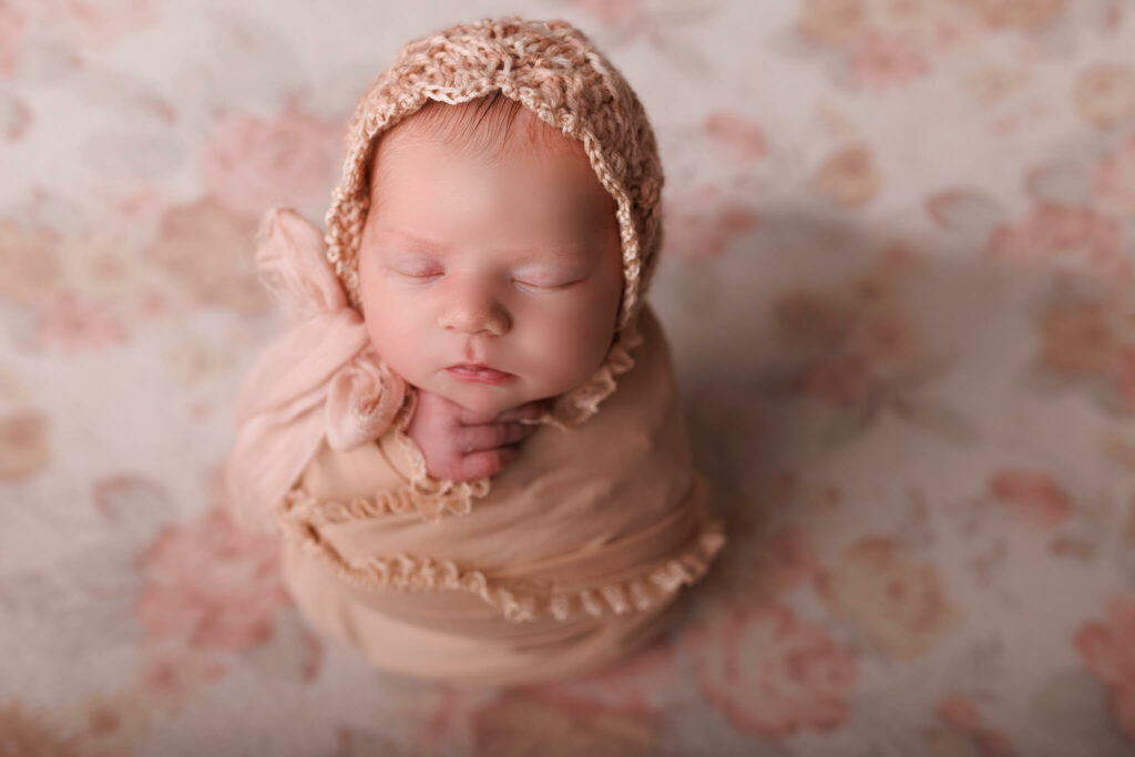 A newborn baby sleeps in a pink blanket and knit bonnet baby strollers toronto