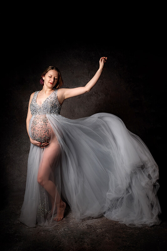 Toronto Maternity Photo Dramatic photo of an expecting mother with flowing motion in the skirt of her silver gown
