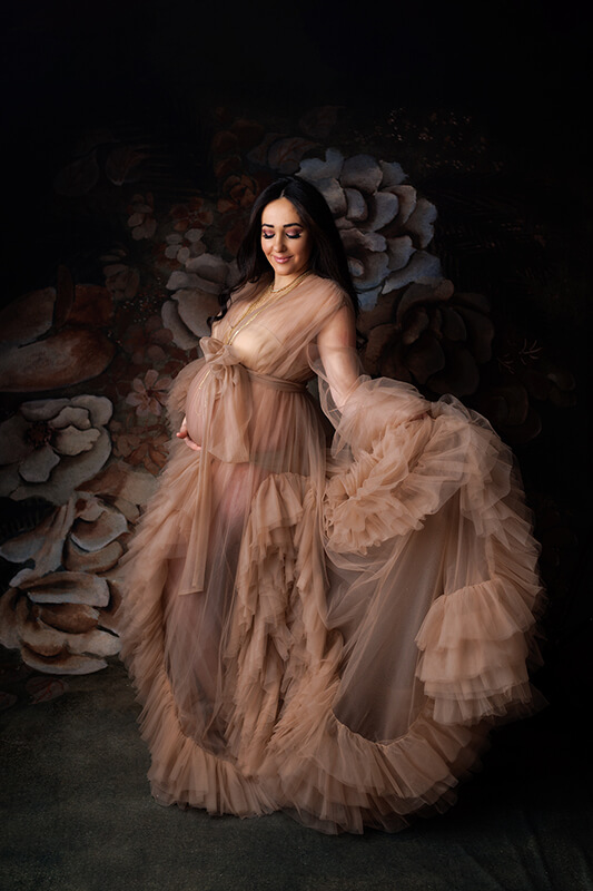 Woman in a tulle maternity robe posing for the camera, holding skirt out
