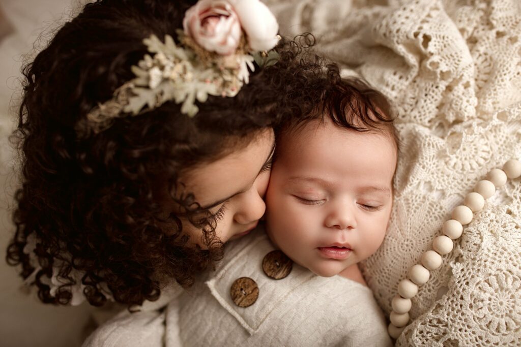 little girl kissing her newborn brother on the cheek