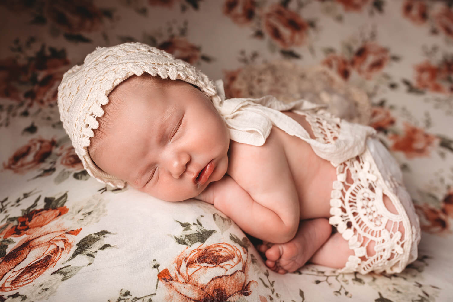Photo of newborn on bed with bonnet.
