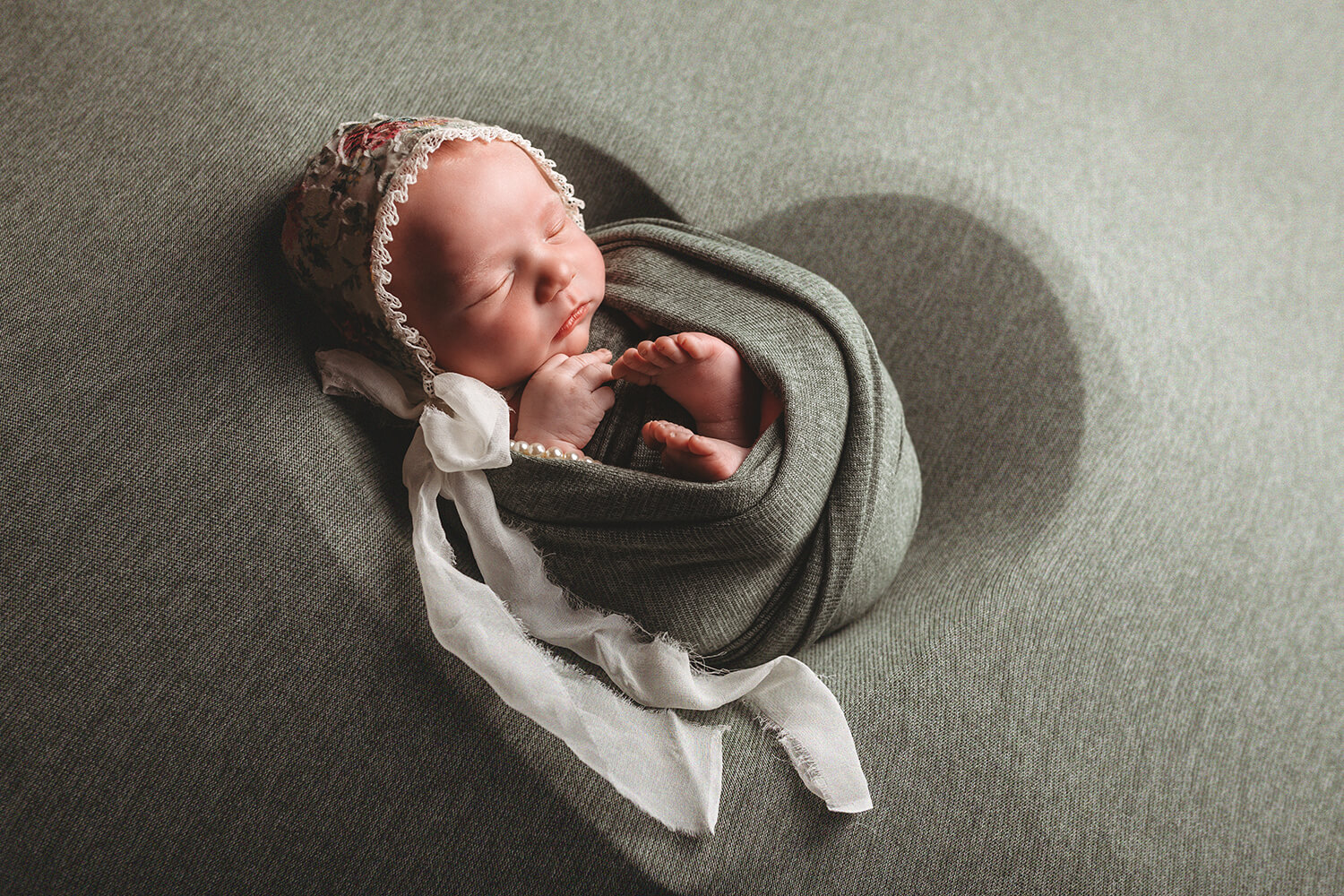 Photo of infant in blanket and bonnet.